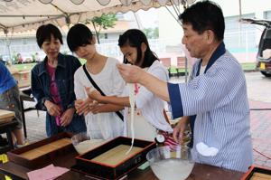 そばの手振りに挑戦する来場者の画像