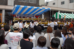 吹奏楽の演奏を披露する生徒と聞き入るおおぜいの観客の画像