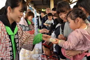 駅で乗客をもてなす市民の画像