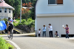 沿道の声援に応えながら坂道を上る自転車の画像