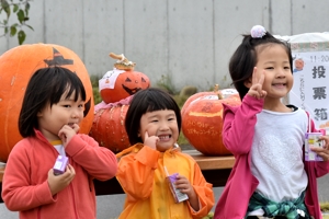 ジャンボかぼちゃの前で笑顔でポーズをとる子どもたちの画像