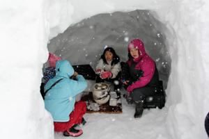 かまくらの中で餅を焼く子どもたちの画像