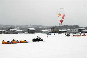 雪上を走るスノーとレインと熱気球の画像