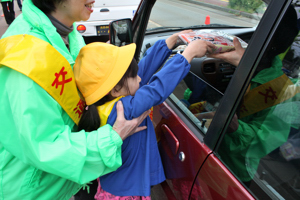 手を伸ばし運転手に交通安全を呼びかける園児の画像