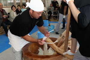 ひもを使い杵についた餅を取り除く作業の画像