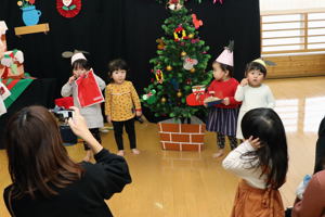 クリスマスツリーと記念撮影をする子どもの画像