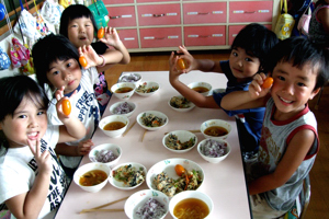 給食に収穫したトマトを食べる園児の画像