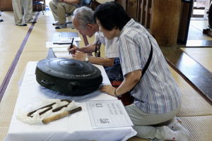 県指定文化財「鰐口」を鑑賞する来場者の画像