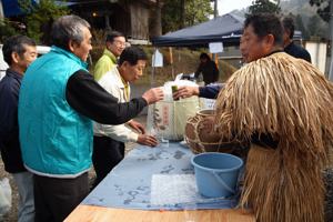 むじな酒をふるまう住民の画像