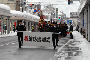 出初式の看板を持ち、行進する消防署員の画像