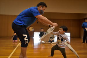 広げた新聞をパンチして破る子どもの画像