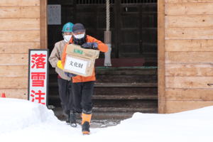 神社から貴重な資料に見立てた箱を搬出する参加者の画像