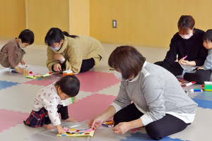 ひなまつりの飾りを作る親子の画像