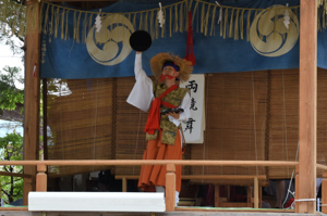 両手に持った盆を落とさずに踊る演者の画像