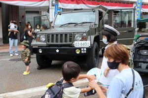 自衛隊車両の前で記念撮影をする親子の画像