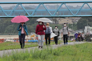 小雨が降る中、信濃川沿いの土手を歩く参加者の画像