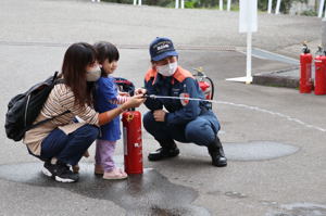 水消火器で消火器体験をする親子の写真