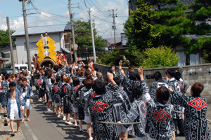 威勢よく筒を引く若者の画像