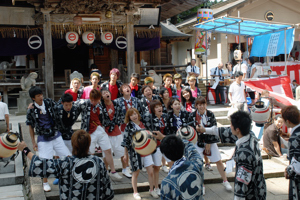 神社の境内で木遣りを奉納する若者の画像