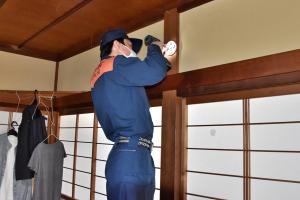 寝室に火災警報器を取り付ける消防署員の画像