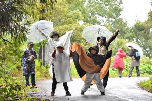 雨の中笑顔でピースサインする参加者の画像