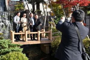 日本庭園の風景と記念撮影をする訪問団の画像