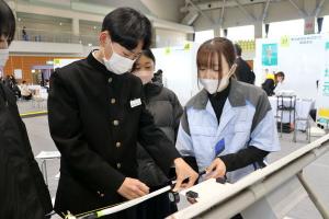 中越住電装のブースで電線に保護テープを巻く体験をする中学生の画像