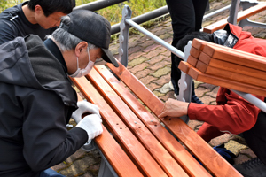 沢山ポケットパークのベンチを修繕する市民の画像