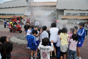 霧状の放水に驚く子どもたちの画像