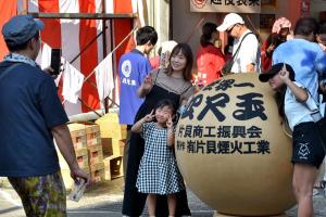 四尺玉の花火玉で記念撮影をする親子の画像