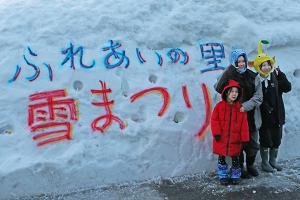 雪の壁に文字が書かれており、その前で記念撮影をする子どもたちの画像