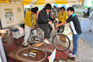 自転車発電体験コーナーで発電用自転車をこぐ来場者の画像