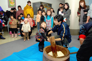 杵を持って餅つきをする子どもの画像