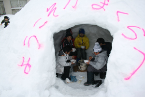 かまくらの中で餅を食べる児童の画像