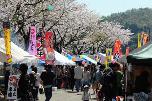 満開の桜とにぎわう露店の様子の画像