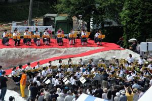 雪山のステージで吹奏楽の演奏を披露する中学生の画像