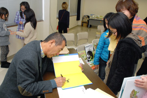 絵本にサインをする松岡さんの画像