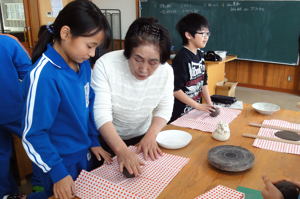 粘土の練り方を教わる小学生の画像