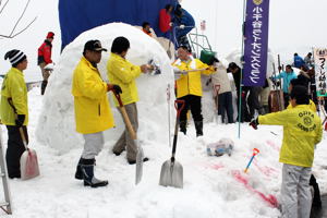 スコップなどで雪像を彫る参加者の画像