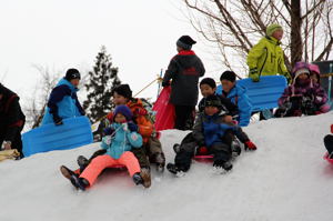 雪のすべり台をすべる子どもたちの画像