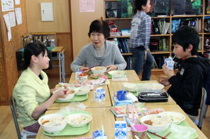 一緒に給食を食べるクラブの方と児童の画像