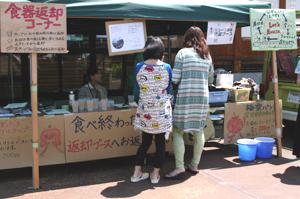 リサイクルのため食器を返却する来場者の画像