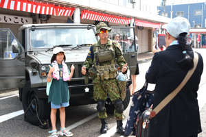 自衛隊と自衛隊車両と記念撮影をする女の子の画像