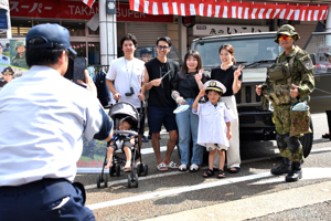 自衛隊と自衛隊車両と記念撮影をする家族の画像